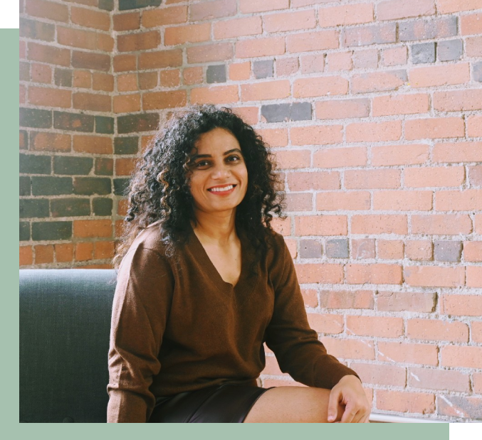 A woman sitting on top of a chair in front of a brick wall.